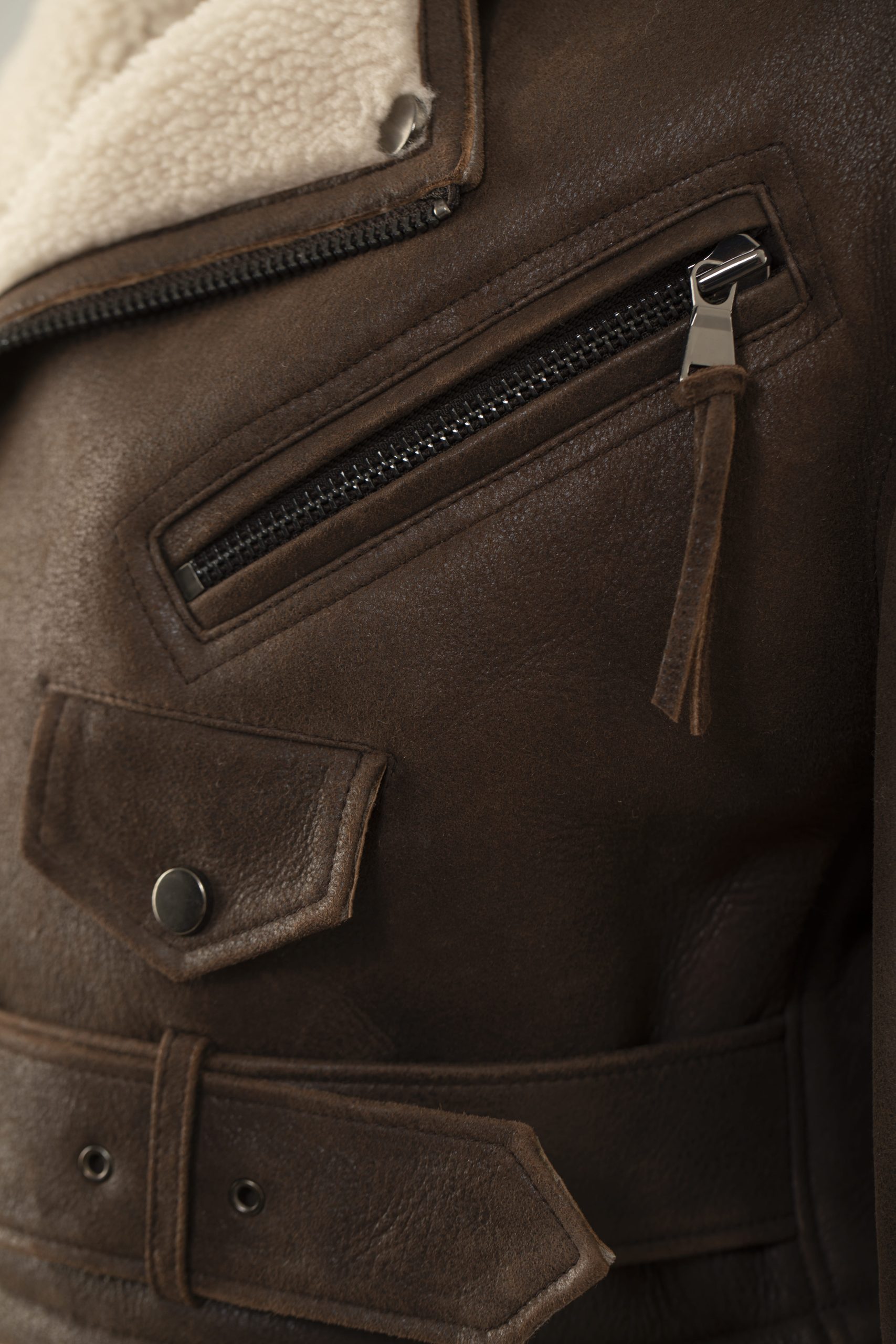 detail picture of a brown biker jacket with zippers and pockets