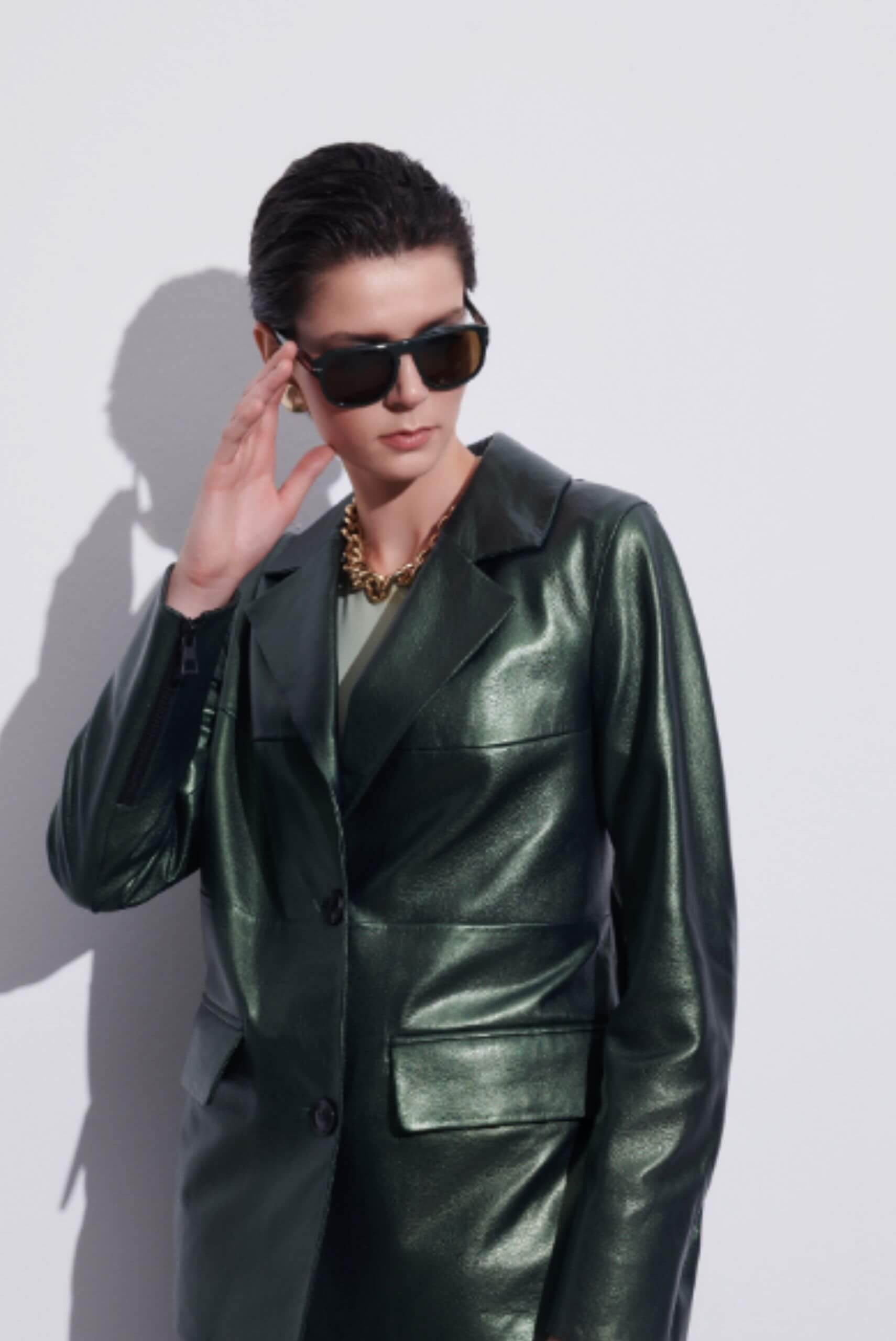 a woman wearing sunglasses and a green leather jacket
