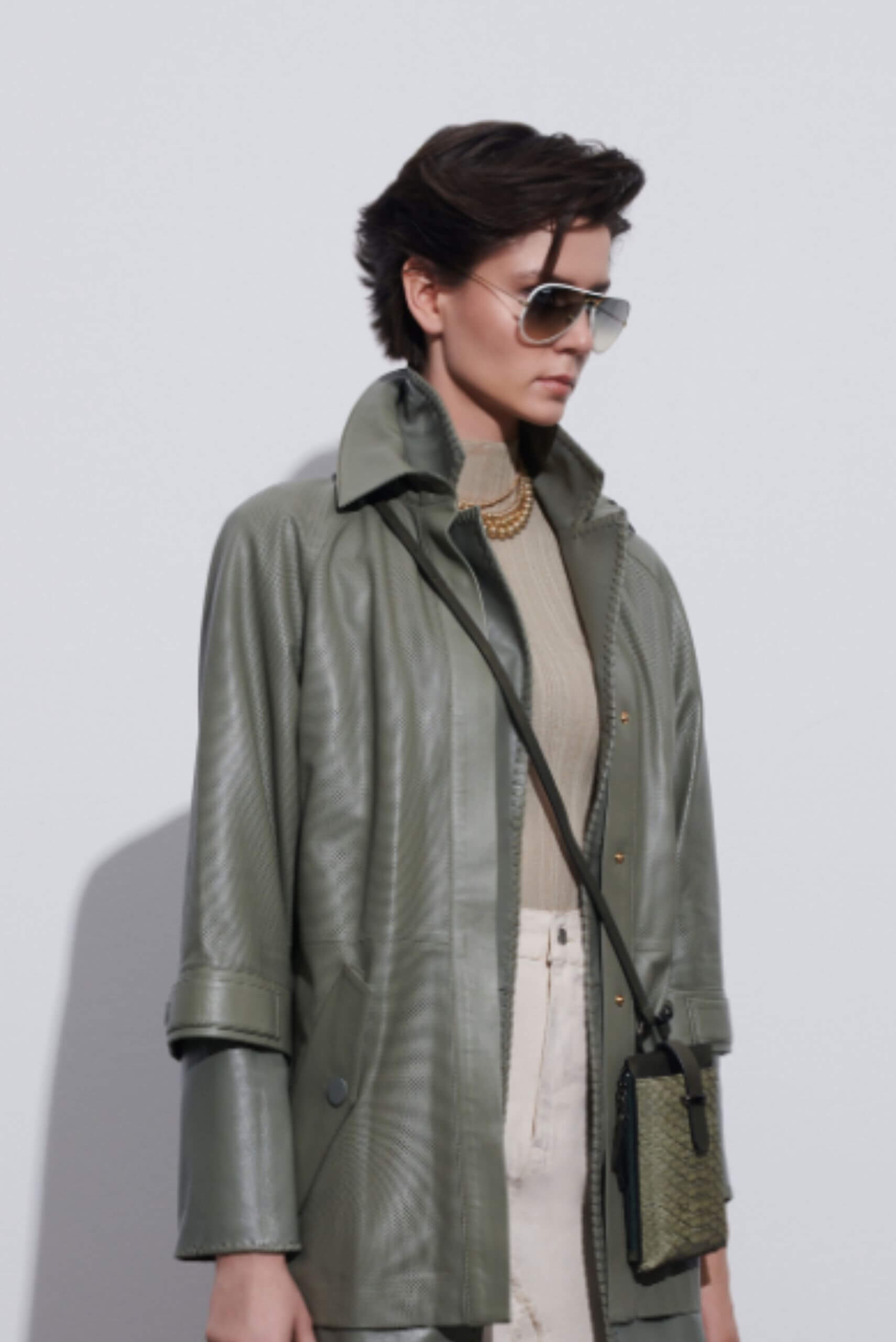 a women with sunglasses wearing a green leather jacket