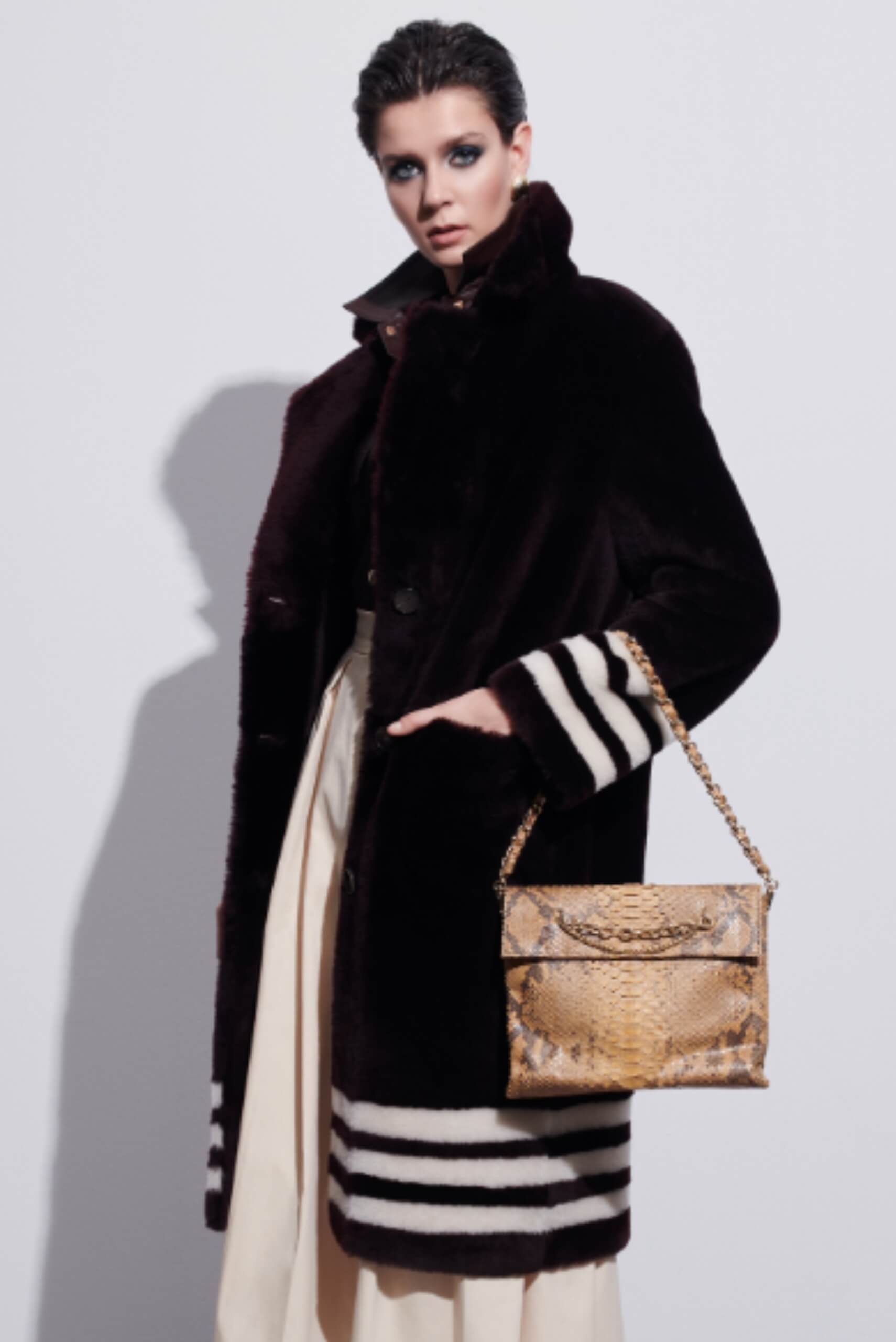 a woman in a black fur coat with a beige handbag